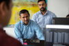Zwei Mitarbeiter der IT-Qualitätssicherung am PC, Code auf Monitor